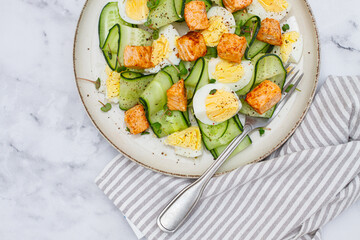 Delicious salmon and egg salad served on a plate with fresh cucumber and herbs for a healthy meal at lunchtime