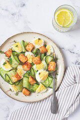 Delicious salmon and egg salad served on a plate with fresh cucumber and herbs for a healthy meal at lunchtime