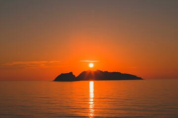 Sunset over sea with island silhouette