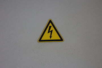 High voltage lightning triangle safety sign on electrical cabinet door, black yellow electrical energy warning label isolated image