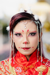 Close-up portrait of woman in red Chinese wedding dress with creative rabbit makeup