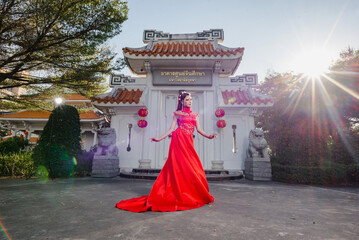 Woman in traditional Chinese dress standing at temple gate with sunlight in background