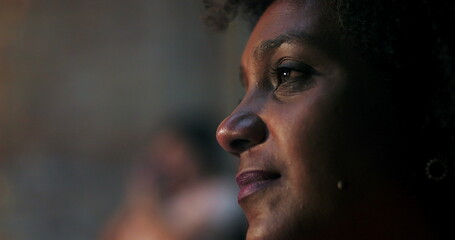 Close-up of woman with curly hair, emotionally moved during spiritual moment in church, illuminated...