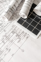 sustainable architecture tools and materials: blueprints, solar panel, wood textures, fabric swatches, and stones. Eco-friendly design, conscious construction and green innovation.