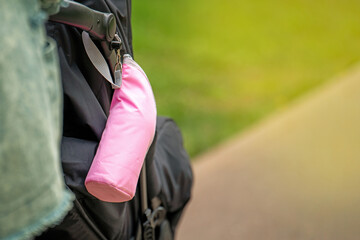 Pink baby bottle container attached to a stroller handle during a walk, showcasing practical parenting essentials