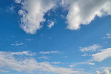 White clouds at the top and bottom of the frame against a blue sky. White clouds at the edges of the frame and bright summer blue sky.