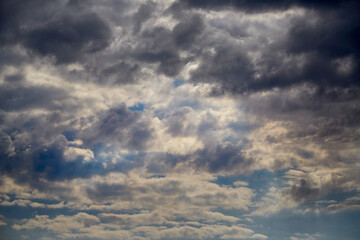 Sunlight breaks through dense clouds in the sky, driven by the wind, a change in weather, sun rays...