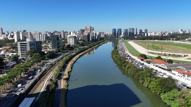 Imagem urbana mostra tr&aacute;fego na Marginal Pinheiros com carros em movimento ao longo do rio e edif&iacute;cios modernos ao redor
