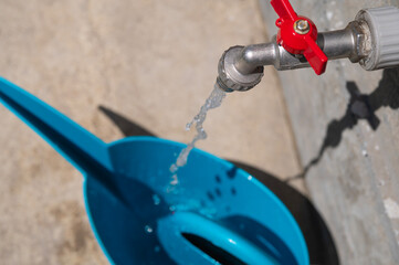 Water flows into a garden watering can, top view. Home garden care concept.