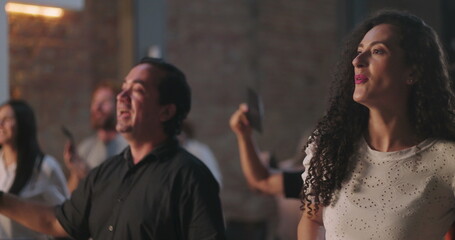 Diverse congregation holding offering envelopes during church worship, Hispanic and African...