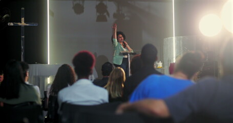 Woman speaking passionately at a church event, raising her hand while addressing the audience, with...