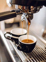 Close-up of an espresso machine dispensing coffee into two cups,  freshly brewed beverage. Barista at work. Espresso coffee. 