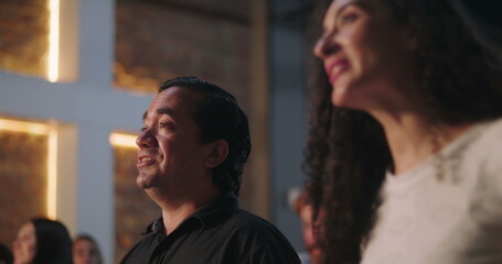 Man of Hispanic descent raising offering envelope in church worship, smiling with joy, illuminated...