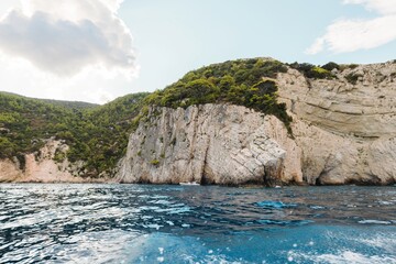 Summer adventures unfold in Zakynthos as visitors navigate the vibrant blue waters near majestic cliffs. Sunlight dances across the waves, inviting exploration and relaxation amidst nature's beauty