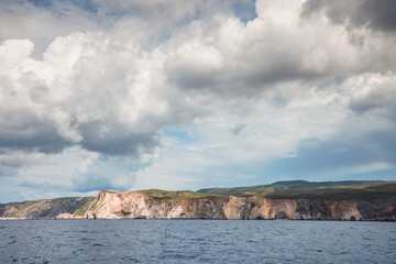 Explore the stunning cliffs of Zakynthos against a backdrop of dramatic clouds and tranquil waters, capturing the essence of summer tourism in this idyllic Greek paradise