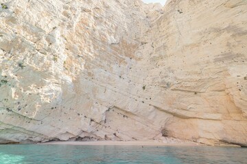 Warm sunlight dances on turquoise waters as visitors explore secluded shores in Zakynthos. The majestic cliffs rise dramatically, inviting relaxation and adventure on a perfect summer day