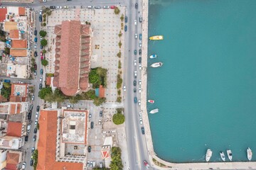 Visitors enjoy the sun-kissed streets of Zakynthos, where charming buildings and lively boats create a vibrant summer atmosphere along the beautiful coastline