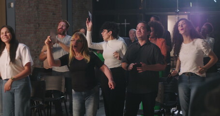 Young woman and older woman placing offering envelopes in church, diverse group in background...