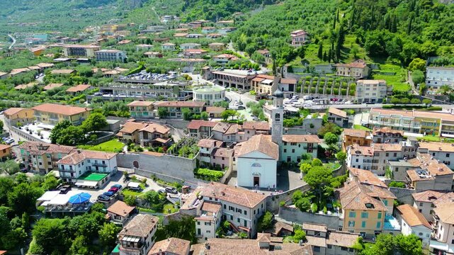 Aerial view of Limone sul Garda, a charming lakeside town with colorful houses, lush lemon terraces, bike paths along Lake Garda, and majestic mountains surrounding the crystal-clear water