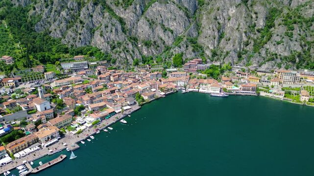 Aerial view of Limone sul Garda, a charming lakeside town with colorful houses, lush lemon terraces, bike paths along Lake Garda, and majestic mountains surrounding the crystal-clear water