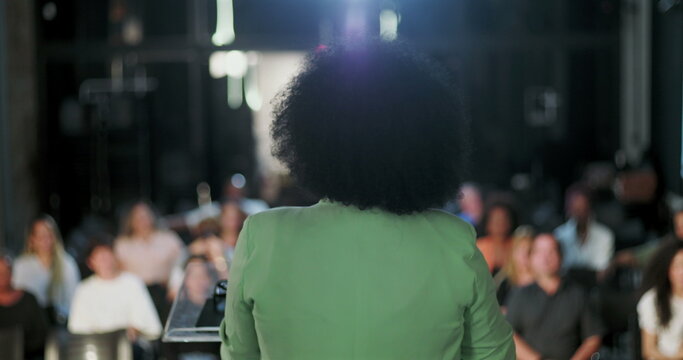 Back view of a woman delivering a speech to an engaged audience, inspiring spiritual gathering, diverse crowd listening attentively to community leader
