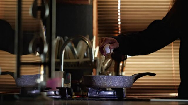 A mid-shot captures a moment of culinary creation as an egg is cracked directly into a hot frying pan on a gas stove, conveying a vibrant and active cooking mood