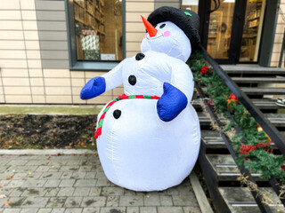 Jolly human-sized snowman dummy decorates Christmas shop in city center. European warm winter without snow.