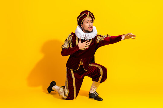A young man dressed in classic royal attire performing dramatically on a bright yellow modern background
