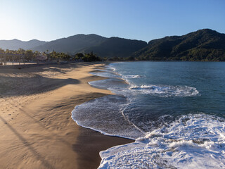 Amazing lighting on orange sand beach and strong waves in coastal village