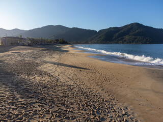 The sun shines on a beautiful morning on the beach with orange sand and strong waves