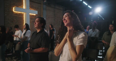 Congregation members with joyful expressions, standing during a Christian church event, reflecting spiritually with a glowing cross in the background