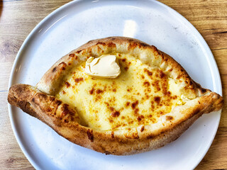 Cheese-filled dish served on a white plate with butter on top at a dining establishment