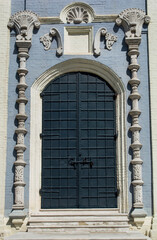 Beautiful door and brick antique wall with beautiful bas-reliefs on a sunny day.