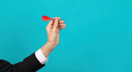 Woman holding a red dart, poised to throw against a blue background. Concept of accuracy, success, and strategic thinking.