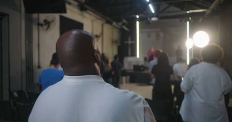 Wide shot of church service with congregation standing and worshipping, back view of people focused...