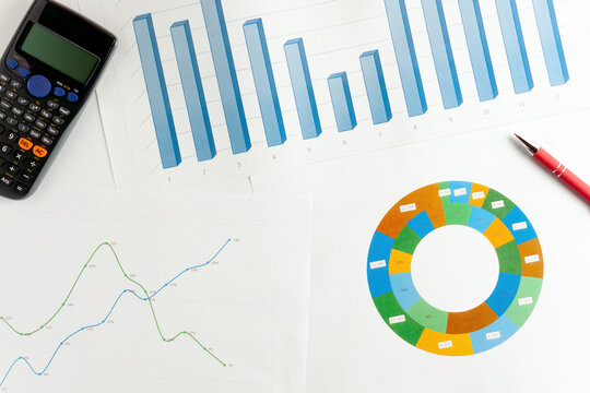 Business charts with calculator and pen on desk
