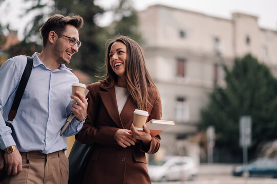 Business colleagues enjoying coffee break while walking and talking outdoors