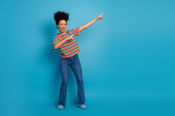 Energetic young girl in striped t-shirt and jeans gestures enthusiastically against a turquoise...