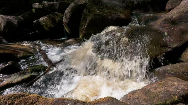 Close-up view of Burbage Brook in Padley Gorge, Derbyshire, with foamy water gushing over rocks