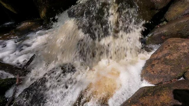 Close-up view of Burbage Brook in Padley Gorge, Derbyshire, with foamy water surging over rocks