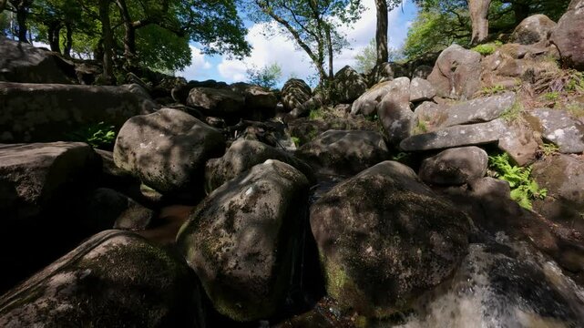 Close-up view of Burbage Brook in Padley Gorge, Derbyshire, with water falling over tufted rocks