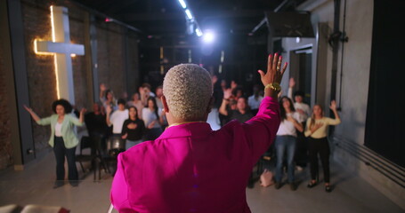 Pastor leading congregation with raised hands in worship, diverse Christian community participating...
