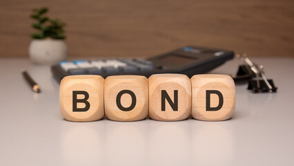 Wooden blocks spelling the word BOND on a desk