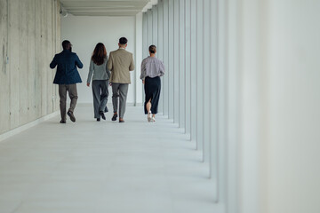Businesspeople walking down modern office hallway