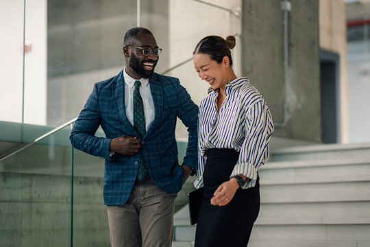 Happy multi ethnic business people walking and talking in office building