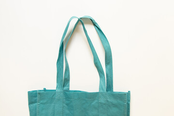 Turquoise eco-friendly fabric bag with long handles on white background, eco-friendly alternative