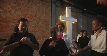 Participants holding hands in prayer during church service, spiritual connection, group praying in...