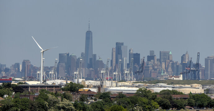 windmill in bayonne new jersey with view of downtown manhattan new york city skyline haze hazy nyc electric electricity wind mill hydro