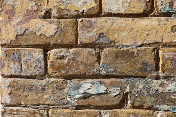 Weathered brick wall displays layers of paint and texture in an urban setting during daylight