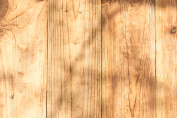 Natural wood surface with shadows highlighting texture and grain patterns in sunny light